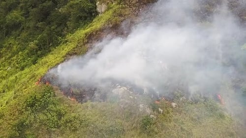 Panorama of vegetation fire on mountain with lots of smoke. Aerial pan right