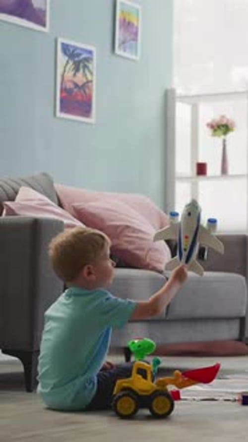 Un niño pequeño juega con un avión mientras un niño en edad preescolar construye una pared