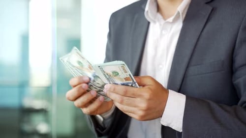 Close up. Male hands count one hundred dollar US bills. Young businessman in formal suit counting