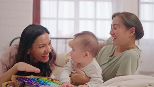 Adults play with baby using abacus on bed