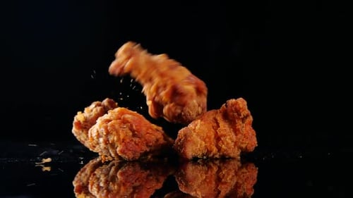 Fried Chicken Pieces Dropping on Black Surface