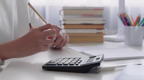 Schoolgirl Using Calculator Doing Homework at Home Office Desk