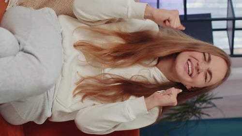 Happy Woman Cheering on Sofa Indoors