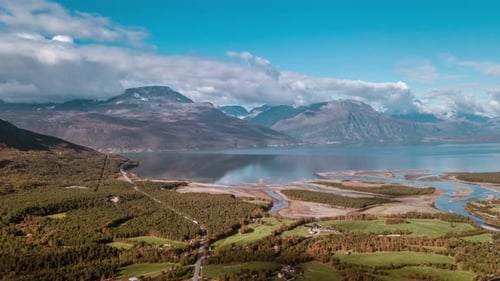 Fjord's coastline. Green fields, small settlements scattered around the landscape. Narrow road cutti