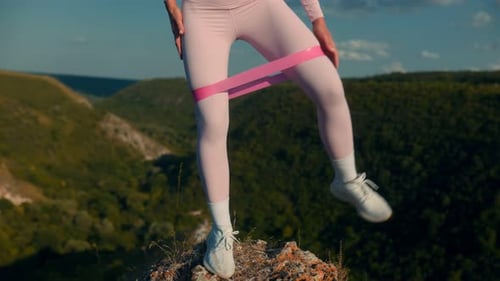 Woman Exercises Outdoors with Resistance Band on Hilltop
