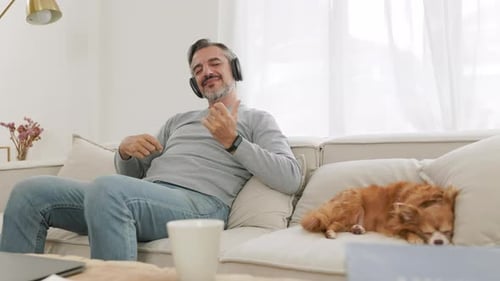 Bearded mature adult man sitting on the couch playing an air guitar