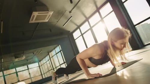 Athletic Girl Doing Push Ups in Spacious Sunny Hall with Windows