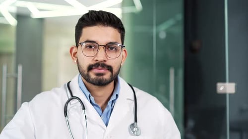 Handsome Doctor Smiling in Bright Hospital Office