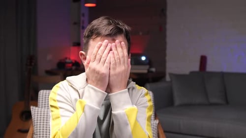 Man Covering Face With Hands Indoors Mid Shot