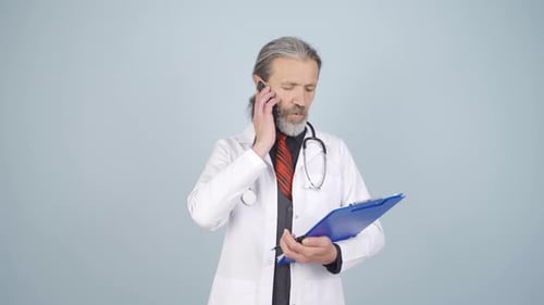 Doctor with Clipboard Answering Phone and Taking Notes