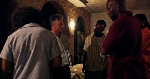 Group gathers inside a wine cellar, barrels visible