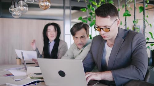 A Diverse Group of Professionals Collaborates in a Modern Office with Laptops Documents and Ideas