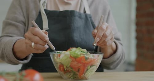 Senior Woman Mixing Fresh Vegetable Salad in Kitchen