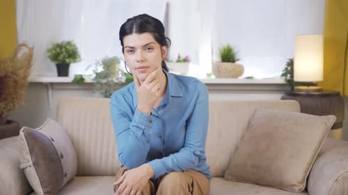 Woman Sitting on Couch, Deep in Thought Indoors