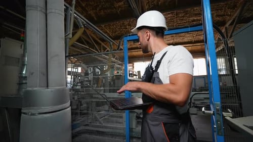 Ingenieurprogrammierer mit Laptop in einer Industriefabrik analysiert den Produktionsprozess