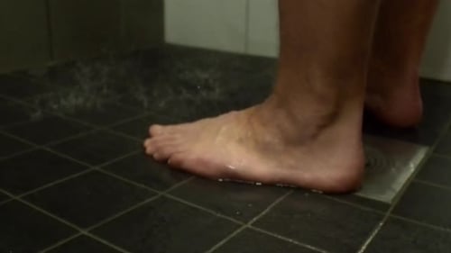 Low angle view of defocused male feet in shower, focus on foreground