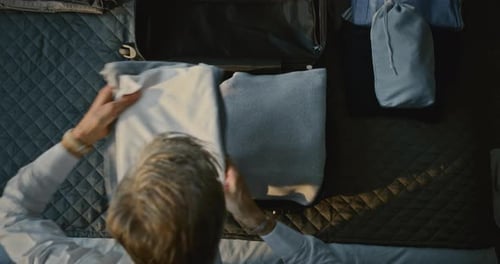 Mature Man Prepares For Journey Neatly Packing Clothes Into Suitcase on Hotel Bed
