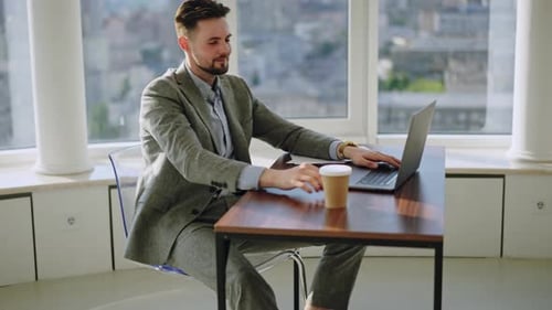 Happy Manager Drinking Coffee at Office Work on Modern Workplace with Big City on Background