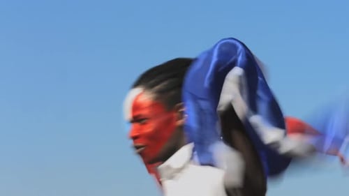 Man Celebrates Holding French Flag in Blue Sky