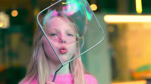 Une petite fille fait exploser une bulle de savon