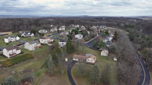 Aerial establishing shot of single family houses in suburb area of american town. Leafless trees in