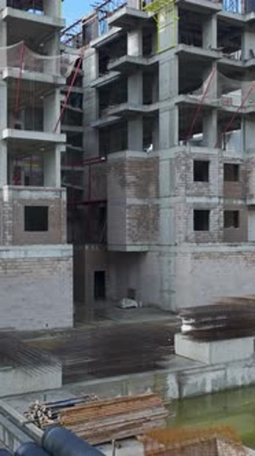 Vertical Video Aerial View of Construction Work on a HighRise Building With Cranes and Workers on