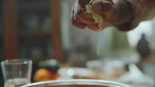 Hand of Chef Squeezing Lime Juice over Paneer Butter Masala in Pan