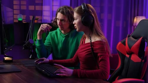 Woman Gaming While Man Watches at Desk