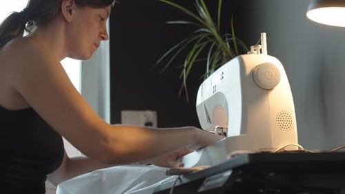 Woman Using Sewing Machine to Work on Fabric