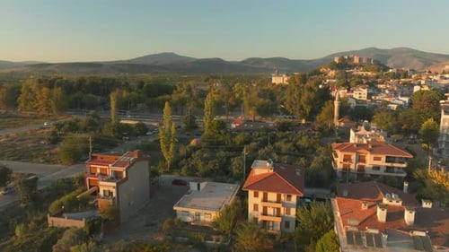Un Drone survole la cime des arbres, dévoilant le château de Selçuk, des montagnes lointaines, à l'heure d'or.