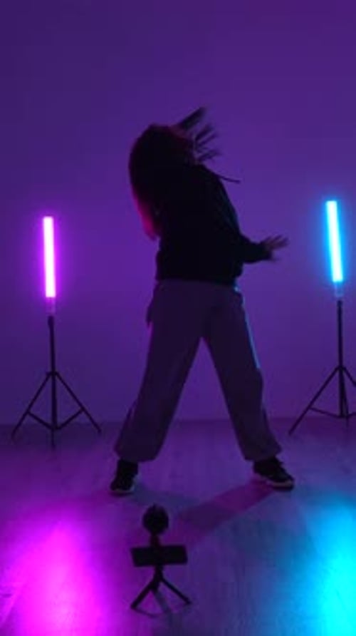 Young dancer performing energetic moves in studio with neon lights