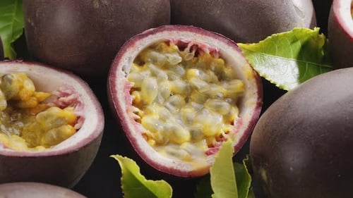 Ripe passion fruits with passion fruit seeds and leaves slowly move in the frame.