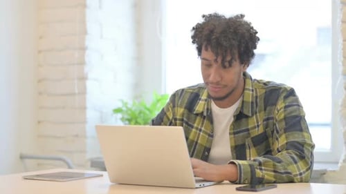 Young Adult Working on Laptop Computer at Desk