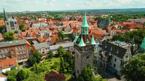 Bustling town with red-tiled rooftops, old churches, and spires stretching across the city under a b