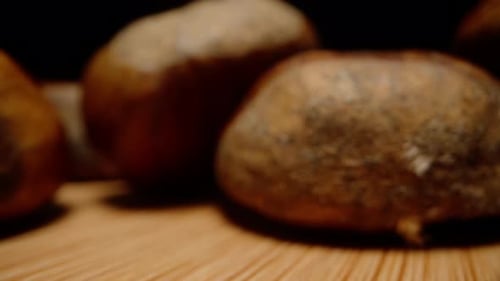 Chestnut nuts are scattered on a wooden table, the camera passes through them, macro.