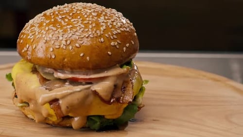 A close-up of a juicy burger with beef patty with vegetables and cheese cooked in the kitchen