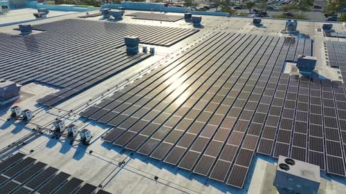 Aerial View of Solar Power Plant with Blue Photovoltaic Panels Mounted on Industrial Building Roof