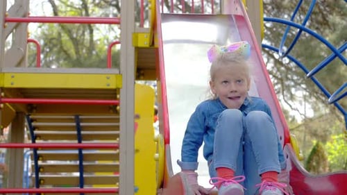 Girl plays having fun on the slide at the playground