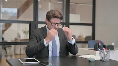 Middle Aged Businessman having Headache while Sitting in Office