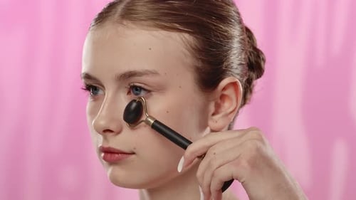 Young Woman Using Facial Roller on Clear Skin in Spa Environment