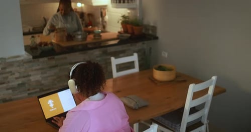 Woman Uses Laptop with Headphones at Home