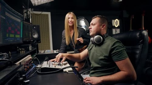 a girl singer and a male sound engineer work together in recording studio to create a new song
