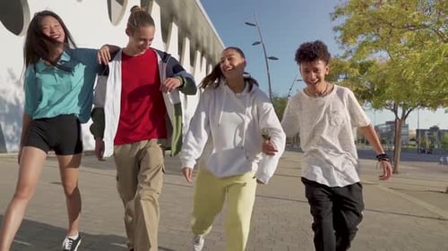 Multiethnic Group of Young Happy Friends Walking Down the Street Holding Each Other Affectionately