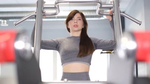 Brünettes Mädchen macht Klimmzüge im Fitnessstudio