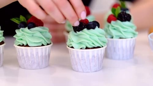 Decorating Fresh Cupcakes with Frosting and Berries