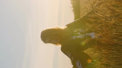Vertical video caucasian romantic woman standing on a wheat field in evening blooming rays of light