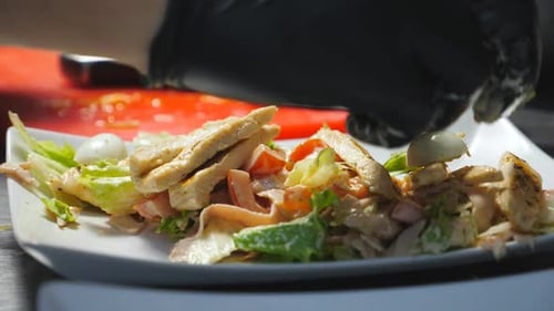 Male Hands Putting Halves of Boiled Quail Eggs Unto Caesar Salad in White Plate at Cuisine Arms of