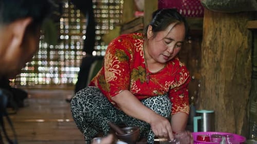 A Lahu Woman From Southeast Asia Prepares Spices for Traditional Food on the Ground Inside a Wooden