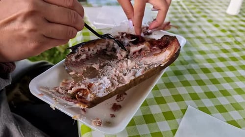 Gegrillter Fisch, der auf einem weißen Teller mit Gabel gegessen wird