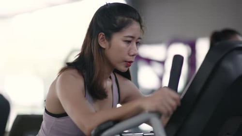 Sport woman is exercising and biking on Stationary Bike in gym.